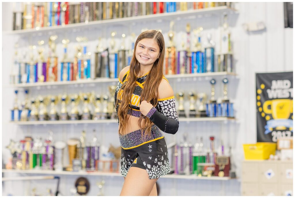 high school senior standing in front of trophies at a cheerleading clinic in Ohio