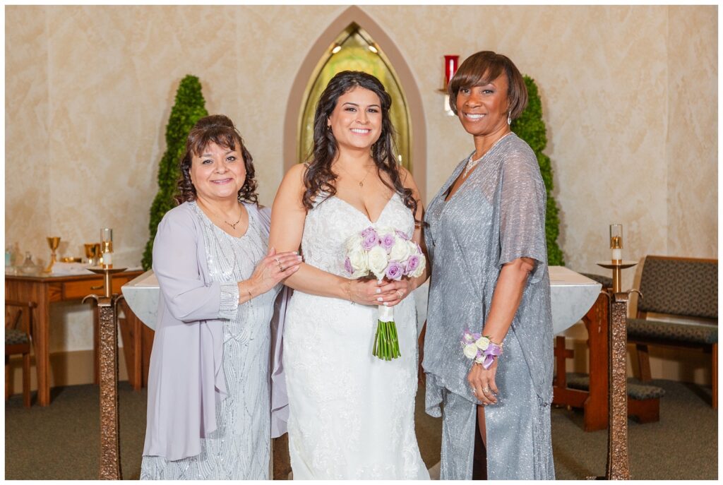 bride posing with both her mom and mother in law at Catholic ceremony 