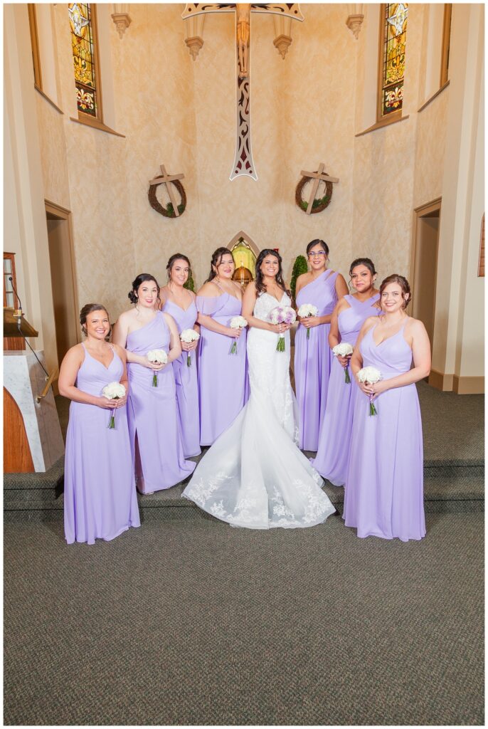 bride posing with the bridal party at church altar in March