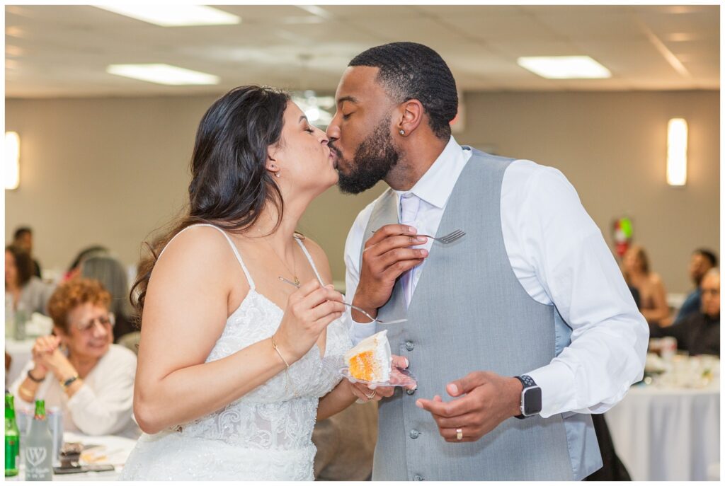 bride and groom sharing cake and a kiss together at spring wedding reception