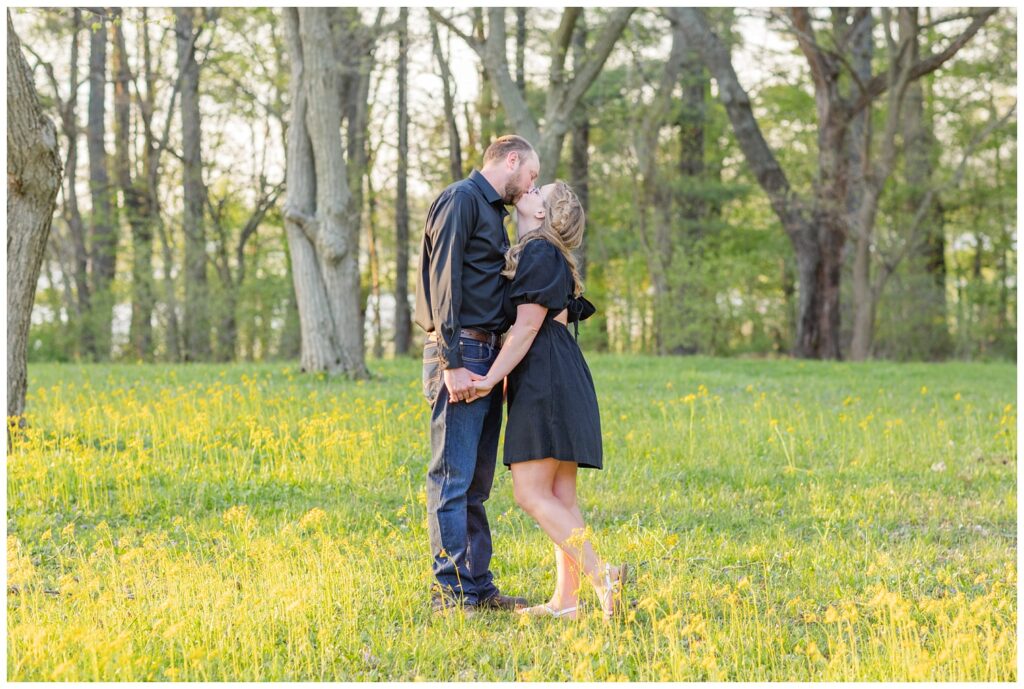 engaged couple kissing in a field at Norwalk Reservoir photo shoot