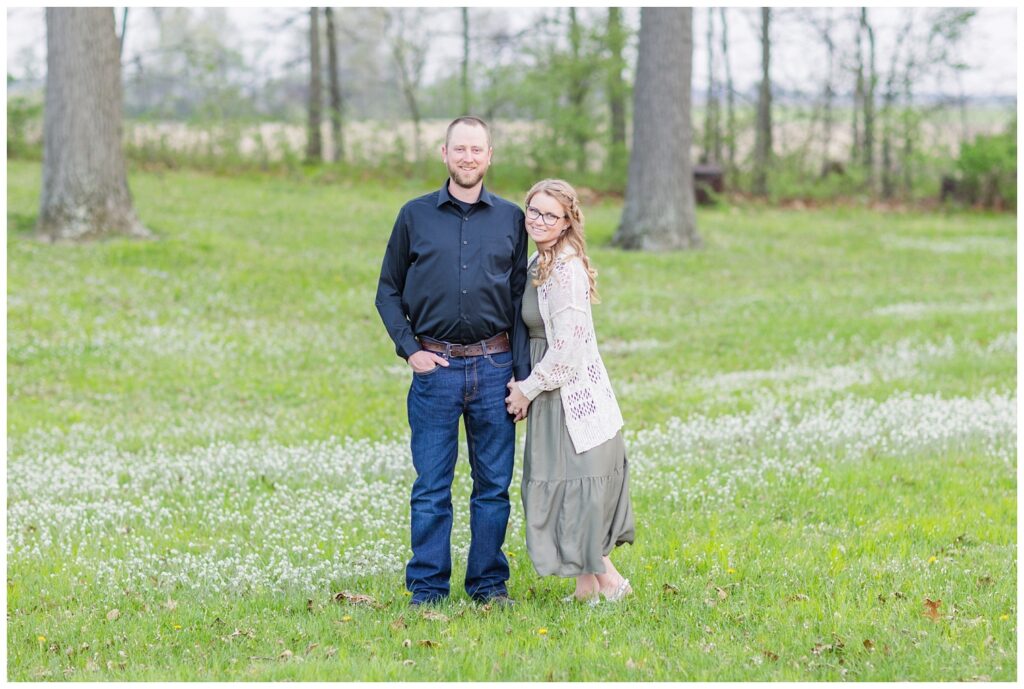 couple smiling together in a field at Norwalk Reservoir engagement photo shoot