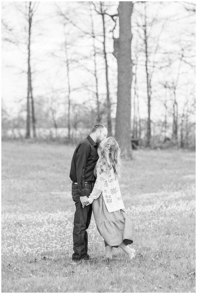 couple kissing in a field at Norwalk Reservoir engagement photo shoot
