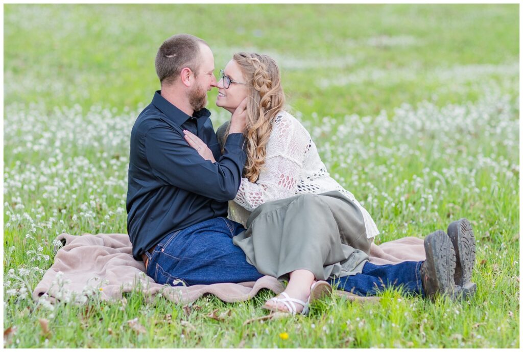 engaged couple posing on a blanket at a field at Norwalk Reservoir 