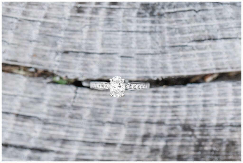 white gold and diamond engagement ring sitting in a wood plank