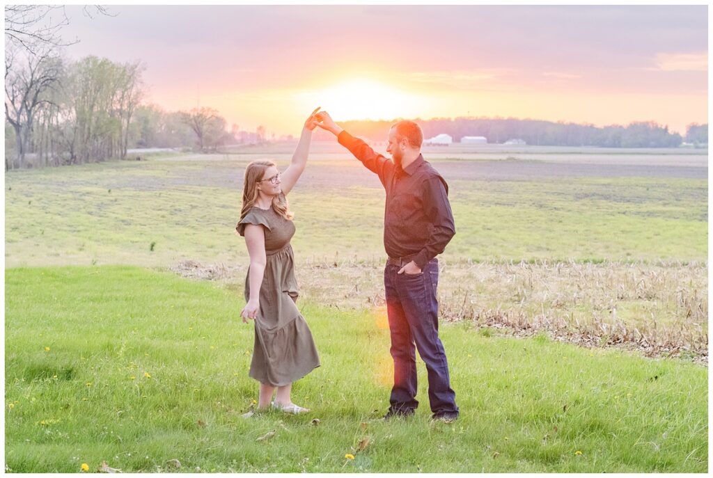 engaged couple twirling in a field at sunset at Norwalk Reservoir 