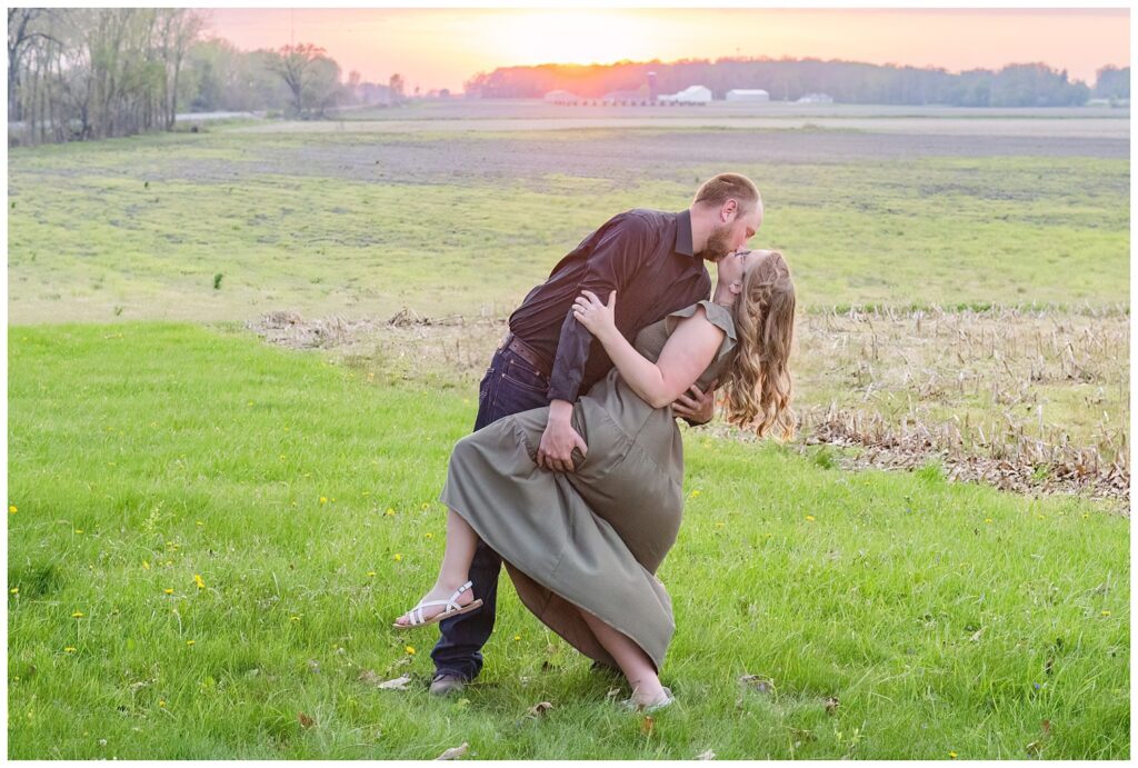 engaged couple dipping back for a kiss in a field at sunset at Norwalk Reservoir 
