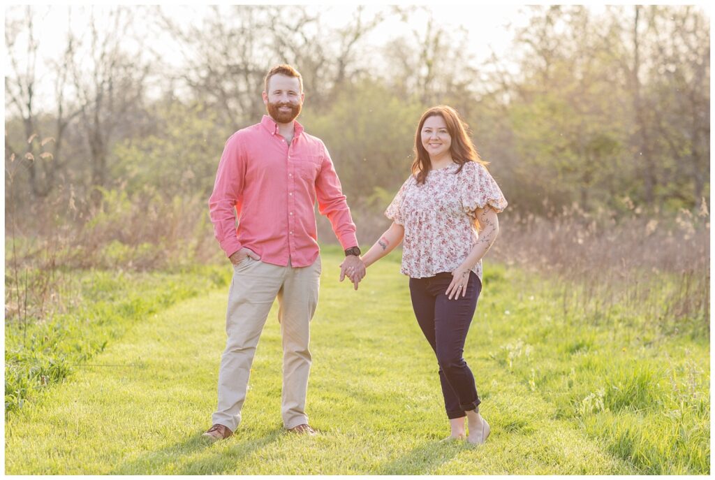 couple holding hands in a green field at Ohio engagement session 