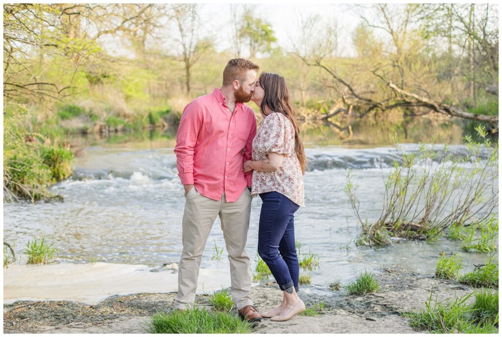 couple kissing while standing near a creek in Lindsey, Ohio