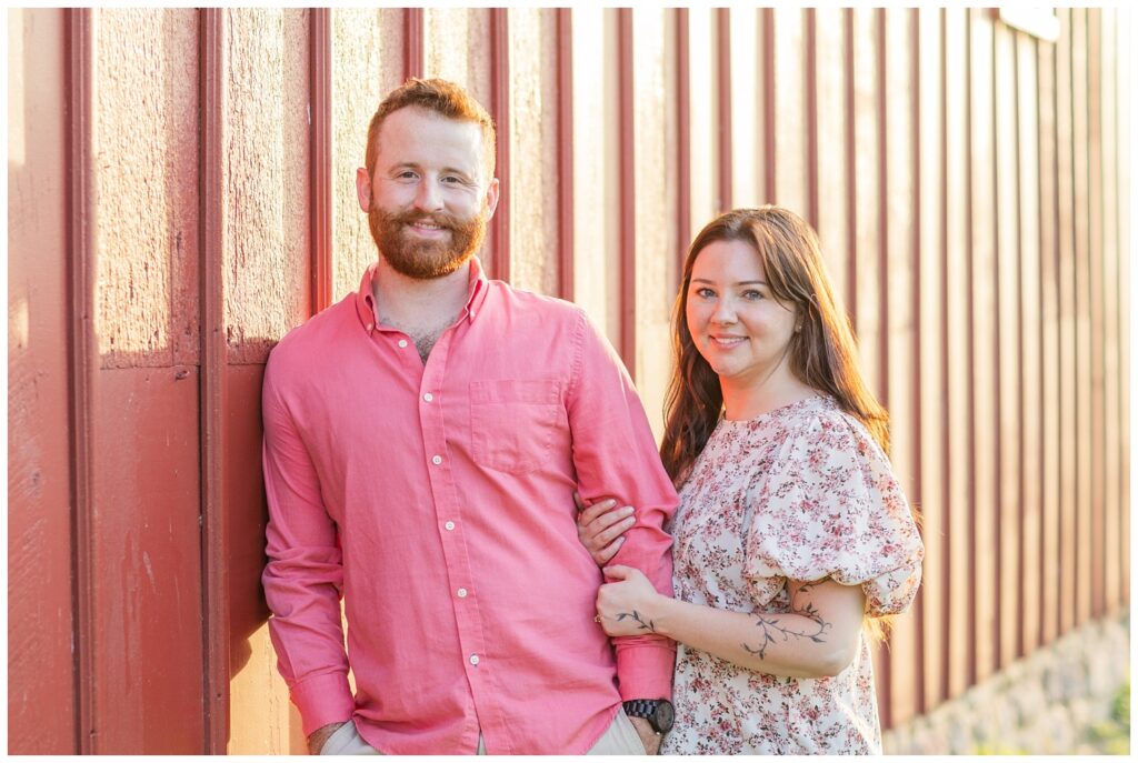 couple posing against the wall of a red barn at Lindsey, Ohio engagement session