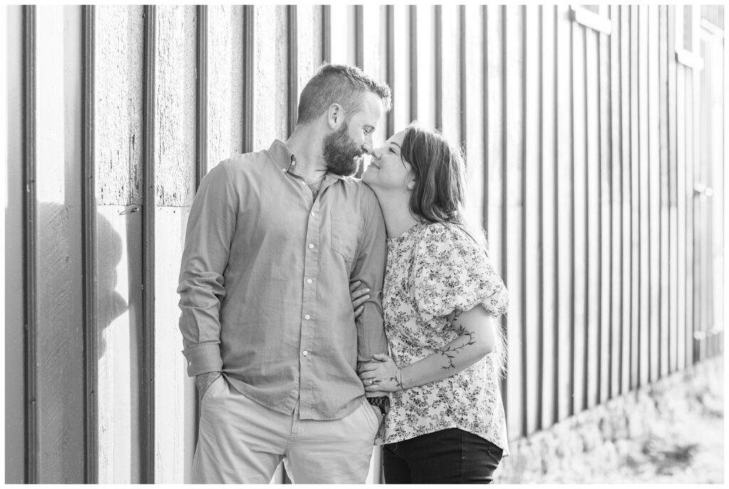 couple posing against the wall of a red barn at Lindsey, Ohio portrait session