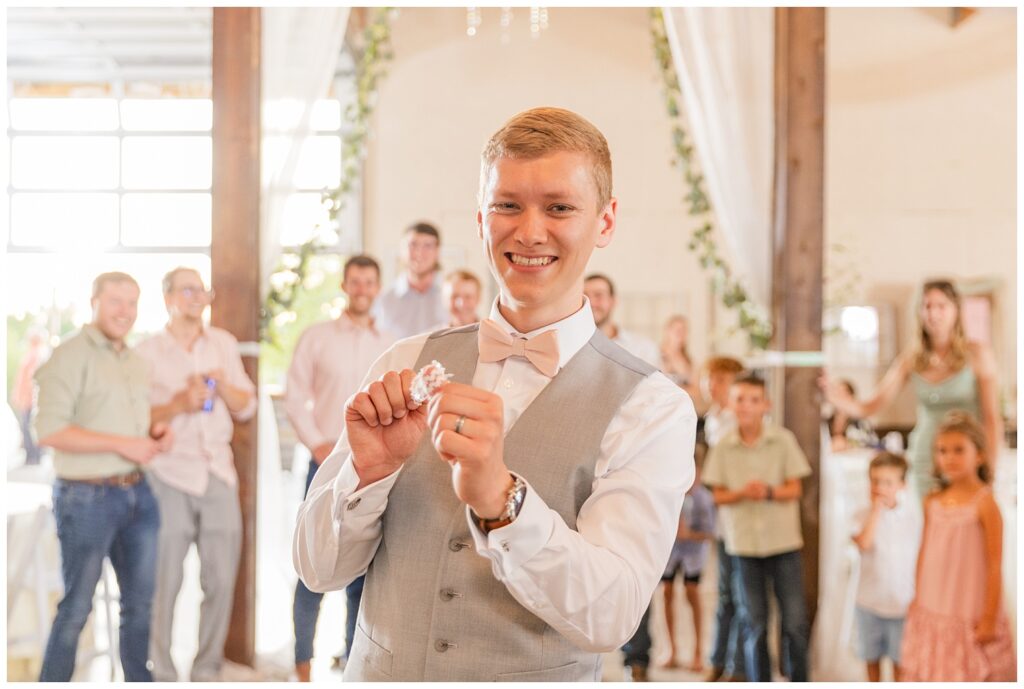 groom tossing the garter to the single men at the barn wedding reception 