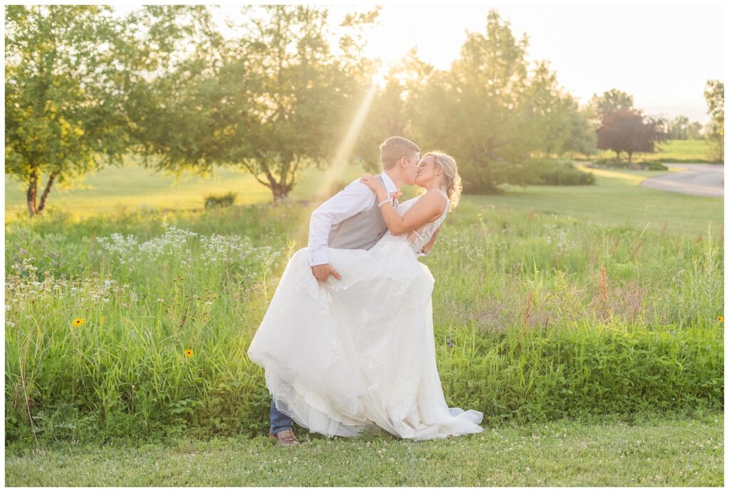 bride and groom dipping back for a kiss in a wildflower field at Prairie Stone Farm venue