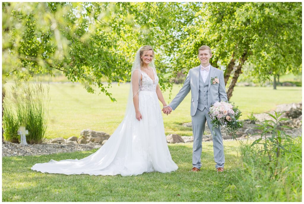 wedding couple holding hands while the groom holds bride's bouquet in West Mansfield, Ohio