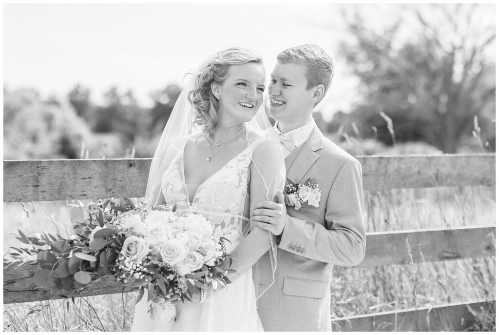 wedding couple posing next to a wooden fence on the venue property in Ohio