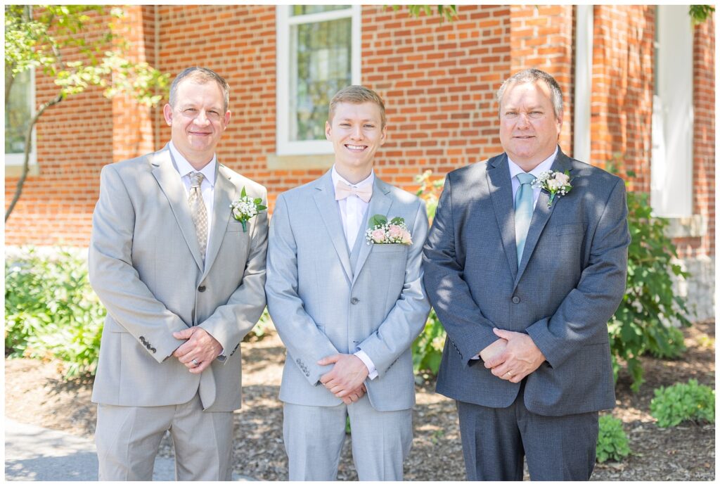 groom posing with his dad and uncle before the wedding outside the church