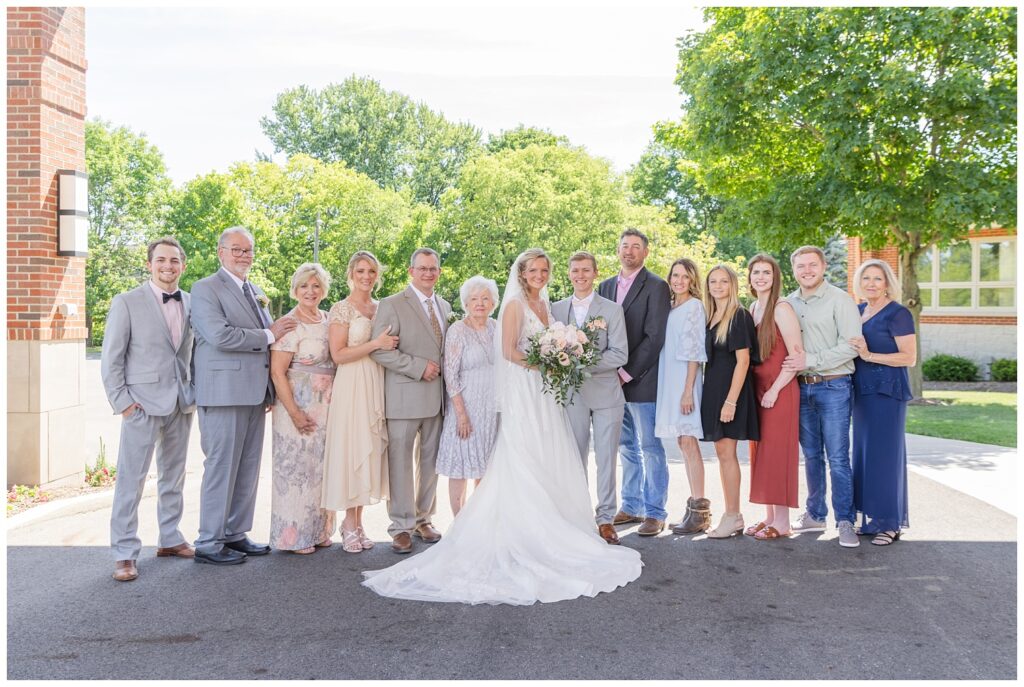 bride and groom pose with the bride's family outside the church after wedding ceremony