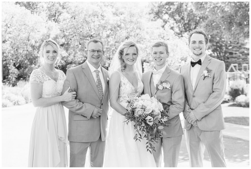 groom and bride posing with the bride's family after a summer wedding in Ohio