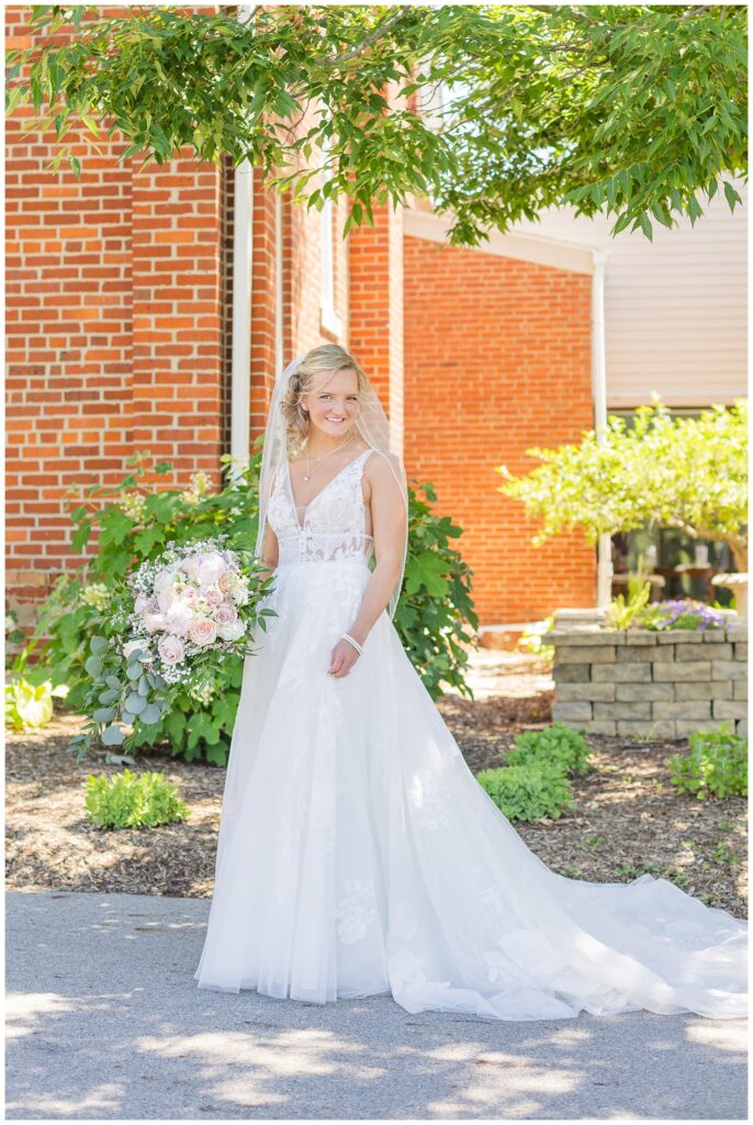 bride posing with her bouquet outside the church before the wedding 