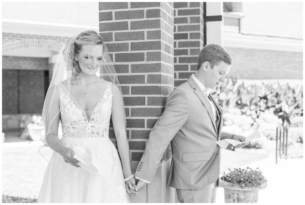 bride and groom reading aloud letters to each other during first touch outside the church