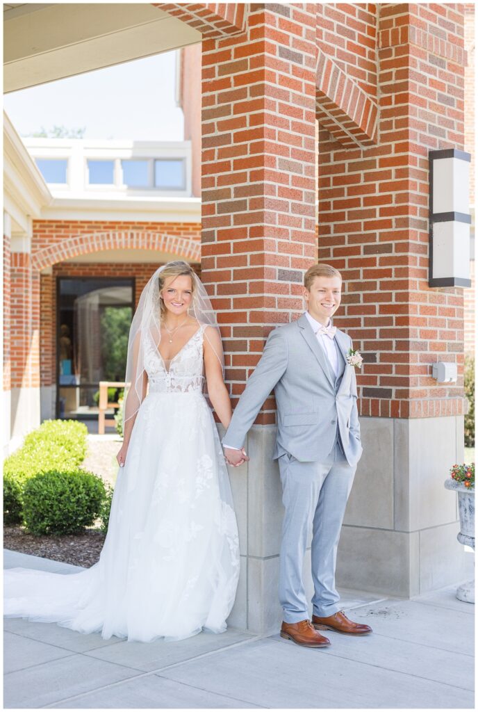 bride and groom sharing a first touch outside the church before wedding