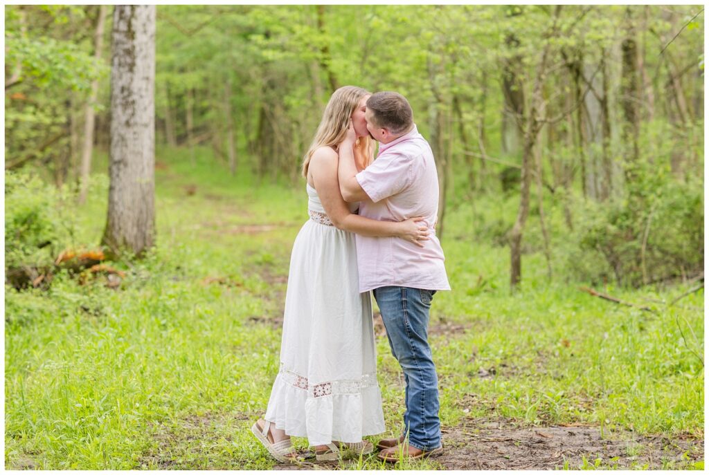 couple share a kiss in the woods at engagement session in Sandusky, Ohio