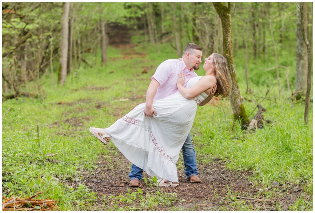 man dipping back his fiance in the woods for a kiss at Ohio engagement session