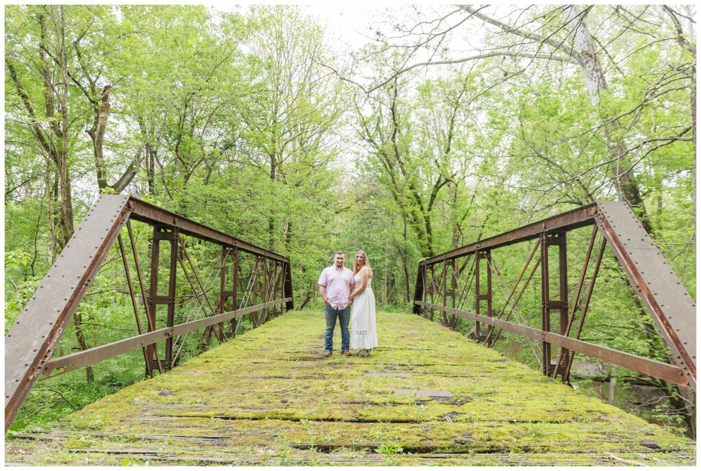 engagement couple standing together on a moss covered bridge in Ohio