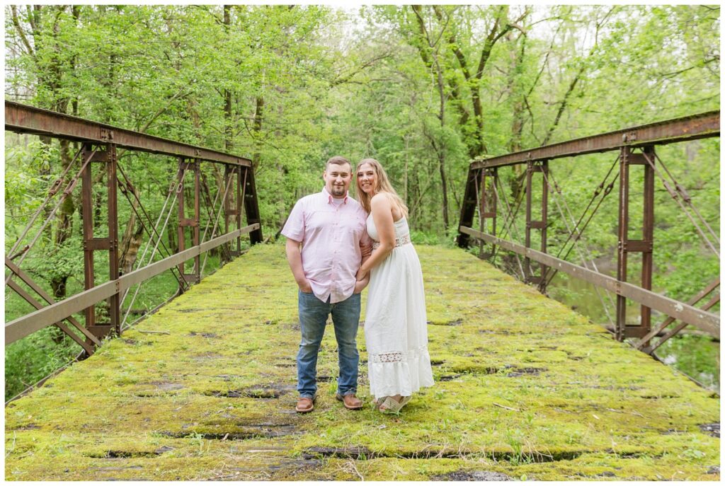 engagement couple standing together on a moss covered bridge in Willard, Ohio