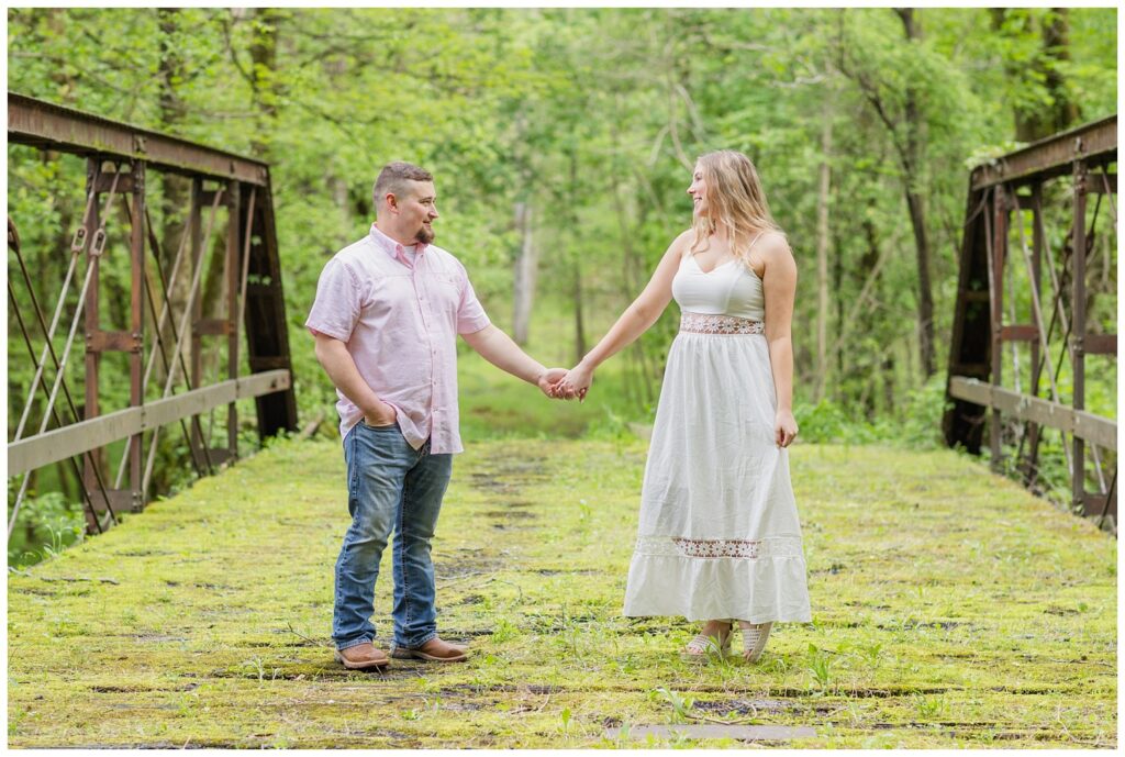 couple holding hands and standing on an old bridge in northwest Ohio