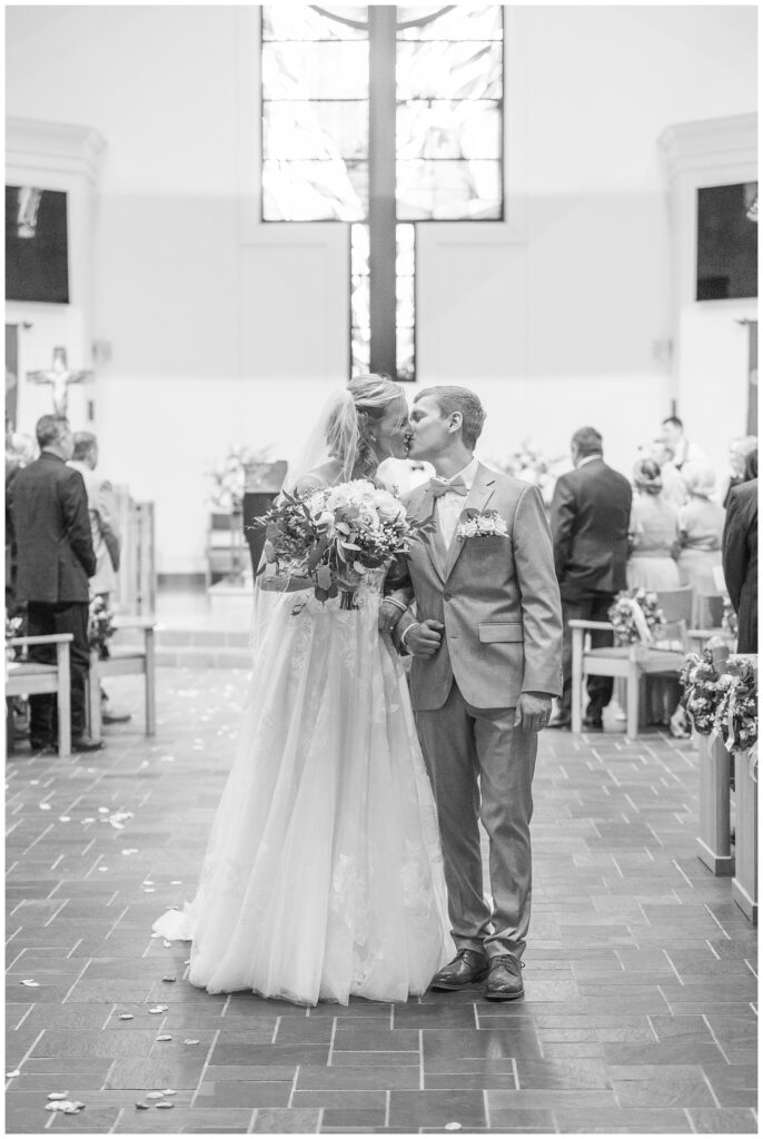 wedding couple share as they walk back down the aisle together after church ceremony