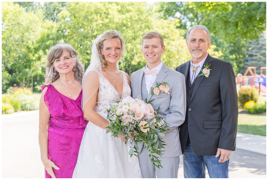 groom and bride posing with the groom's family outside the church in Dublin, Ohio