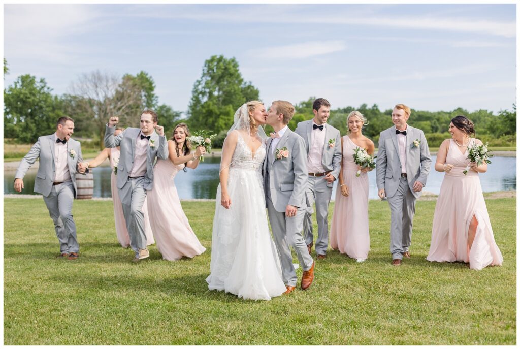 bride and groom kissing while wedding party walks behind them at West Mansfield, Ohio venue