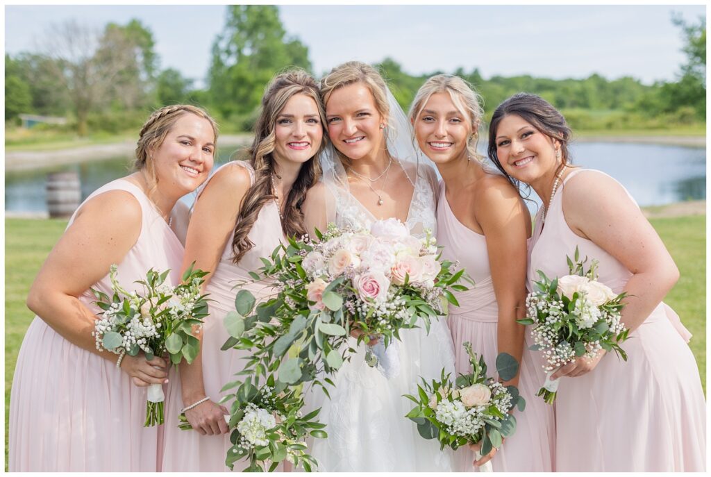 bridal party posing together in front of the pond at Prairie Stone Farm venue