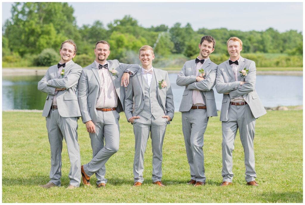 groomsmen doing a informal pose together in front of the pond at Prairie Stone Farm venue