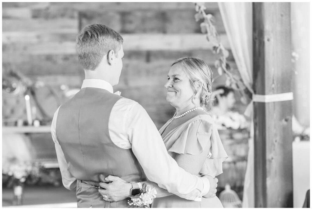 groom dancing with his mom inside the barn reception at Prairie Stone Farm