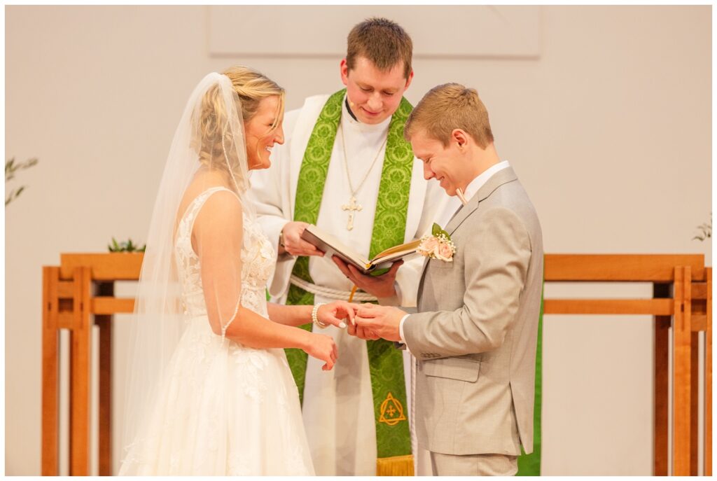 wedding couple smiling while exchanging rings at church ceremony in West Mansfield, Ohio 