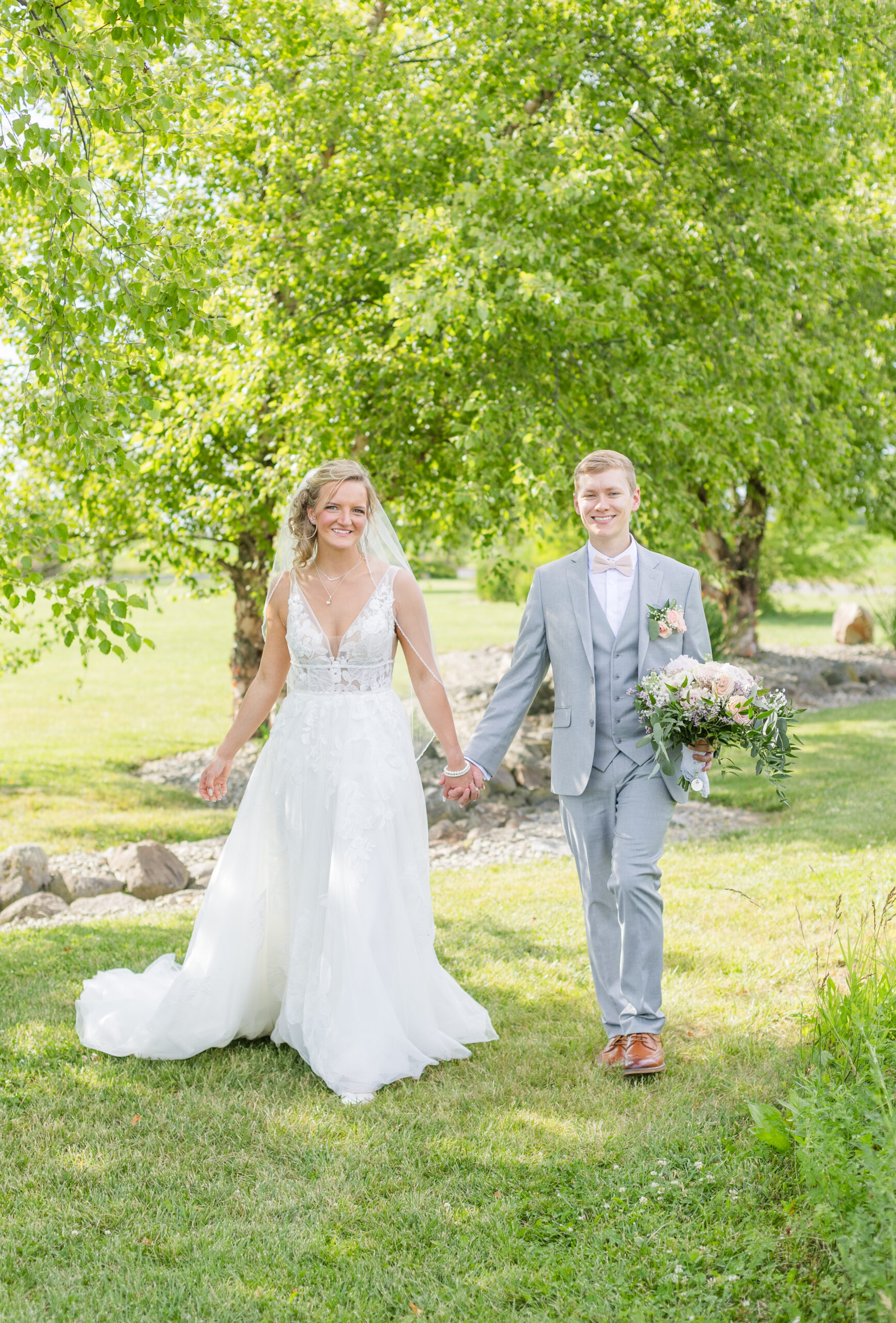 wedding couple walking under a grove of trees at Ohio venue