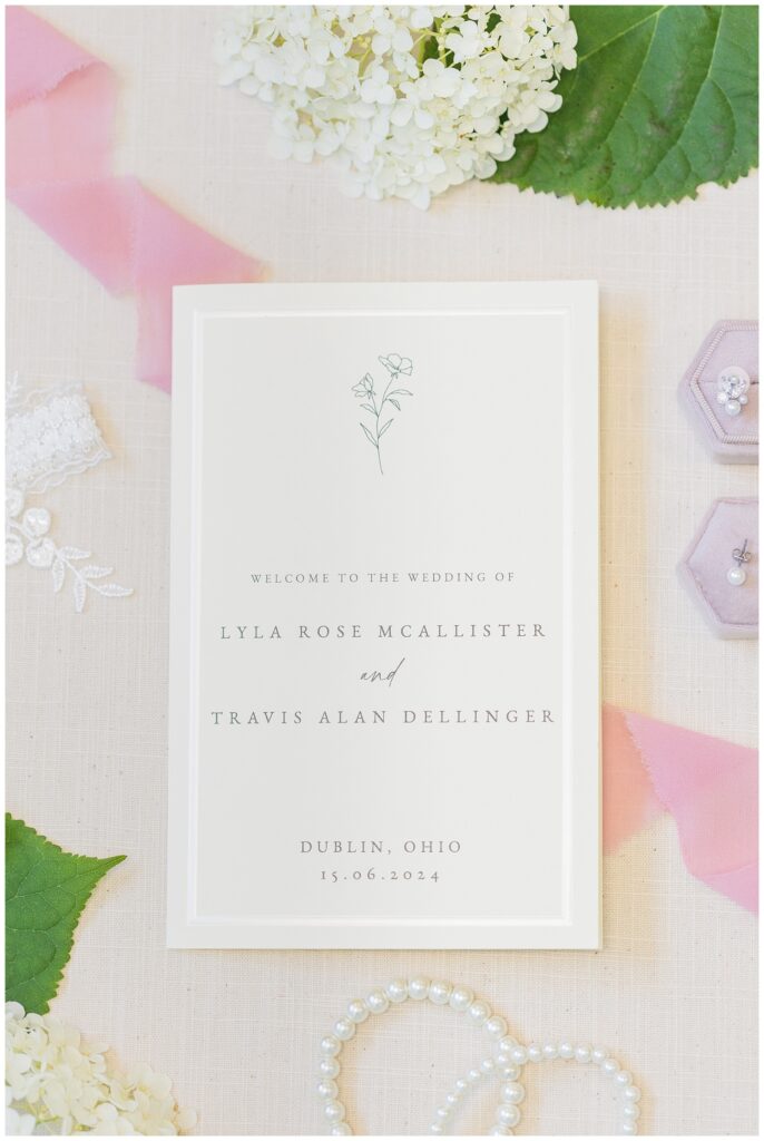 wedding invitation sitting on a beige mat with bridal details in Dublin, Ohio