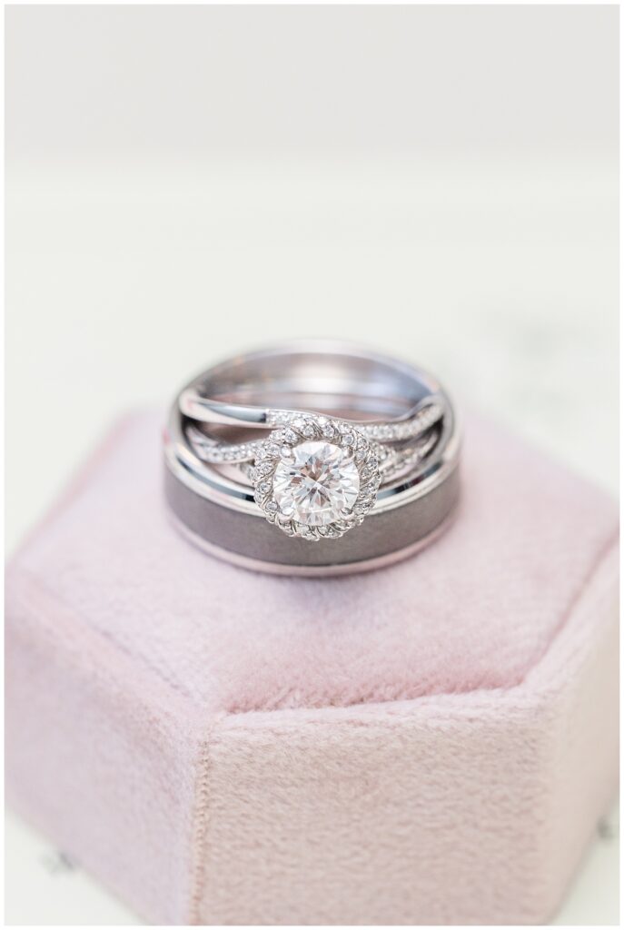 bride and groom's rings sitting on top of the top of a pink wedding ring box