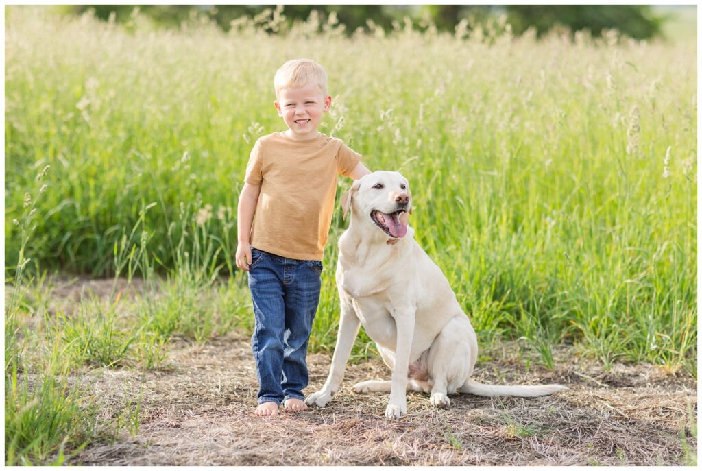 a young boy wearing a yellow shirt standing next to a dog 