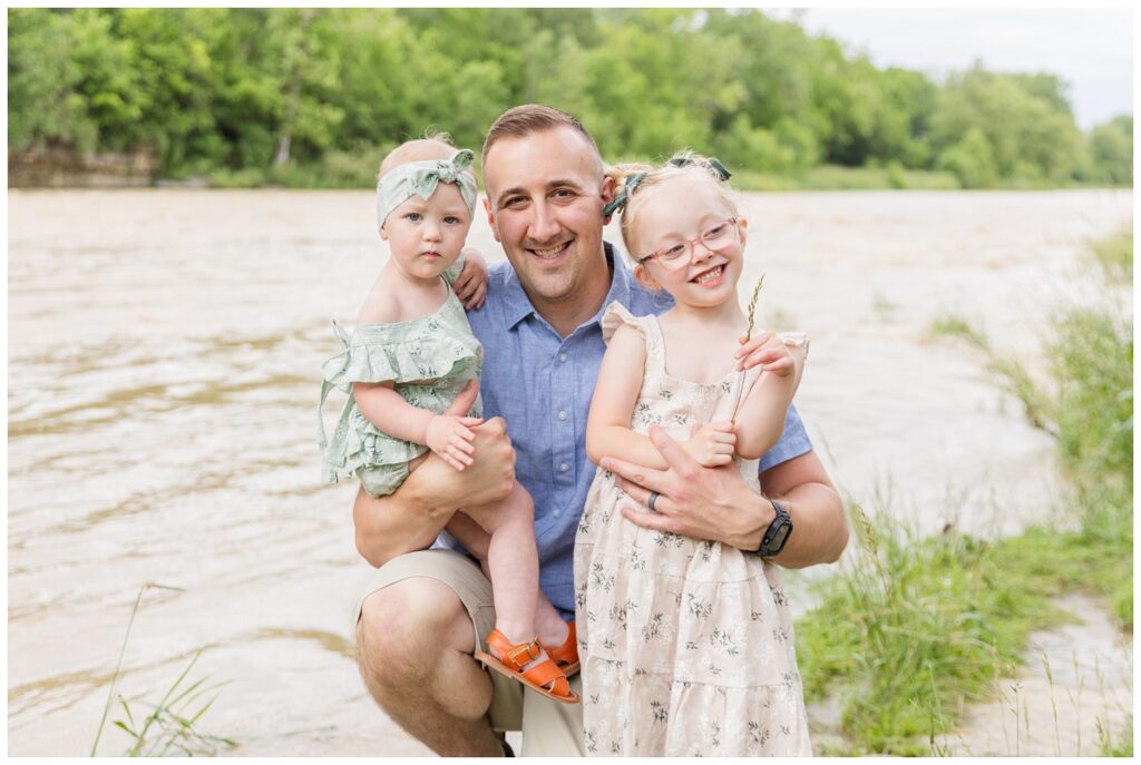 dad holding his two daughters next to a river at Fremont, Ohio family session