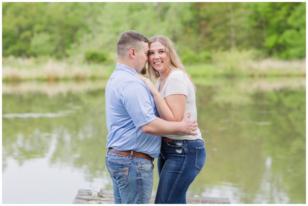 couple smiling while posing on a pond for Sandusky, Ohio engagement session