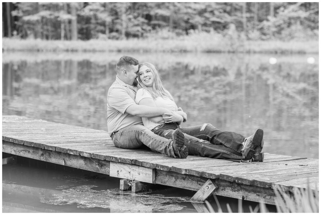 couple sitting on a wooden dock and smiling at Willard, Ohio engagement session