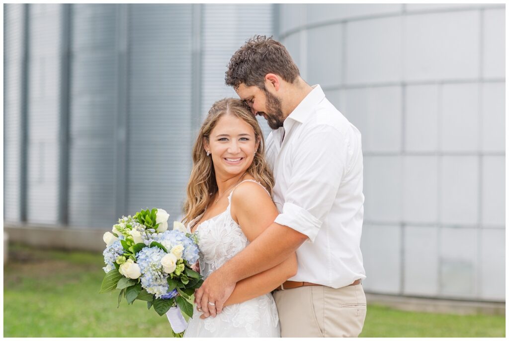 groom hugging the bride from behind while posing on the family farm in Risingsun, Ohio