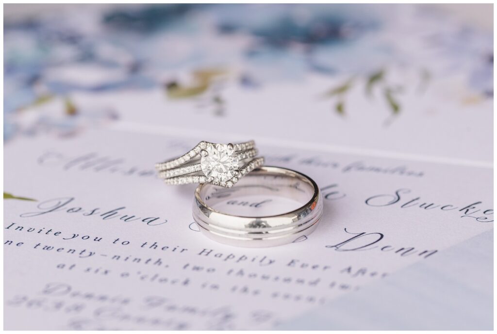 bride and groom's rings sitting on top of wedding invitation 