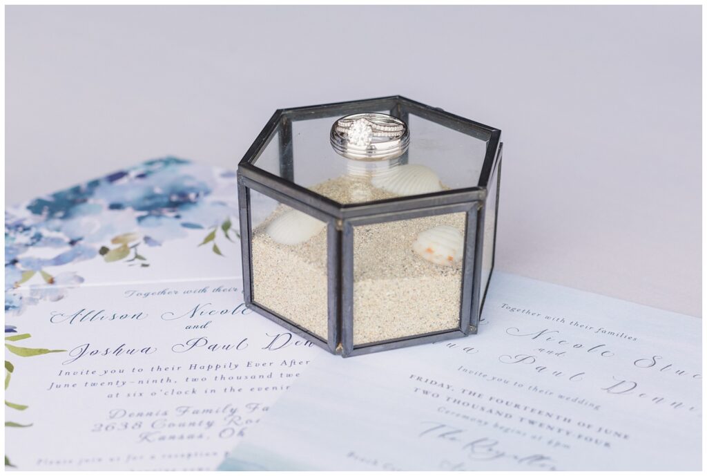 hexagonal box topped with rings, filled with sand and shells from destination wedding 