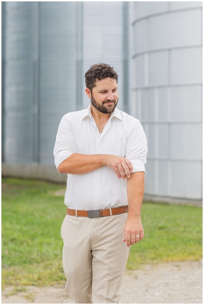 groom rolling up his sleeves, standing in front of a silo in Risingsun, Ohio