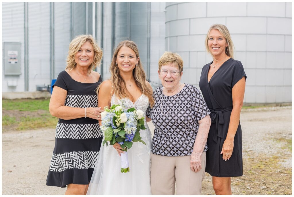 bride posing with her family in front of a silo on her family farm