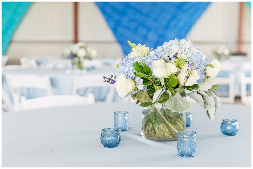 table centerpieces with white roses and blue hydrangeas in vases on top of tablecloth in Ohio